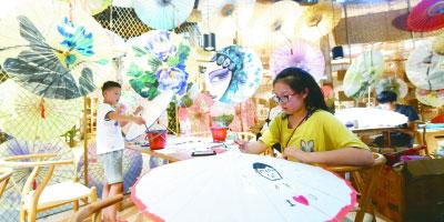 一名小朋友在杭州拱宸桥西历史文化街区手工艺活态展示馆体验油纸伞的制作。新华社发